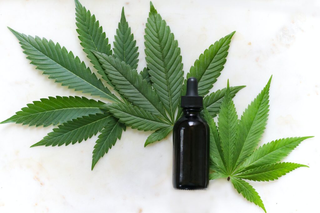 It's hemp leaves on a white background with a black bottle on top - an oil dropper.